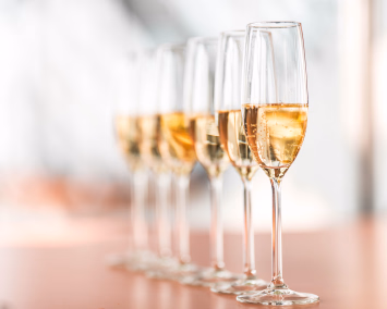 En rekke med glass fylt med musserende vin på et bord