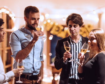 En gruppe mennesker som smaker på musserende vin i et rom med dekorativ belysning