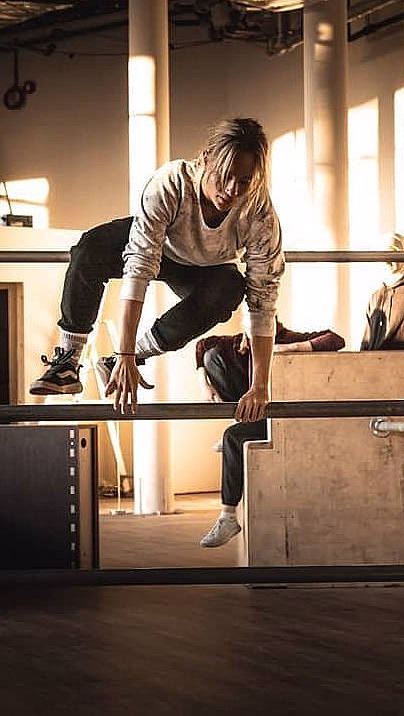 Kvinne som hopper over metallstenger i et parkour-lokale