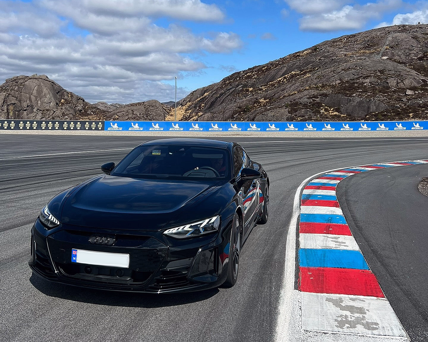 Svart Audi på en racerbane ved siden av en rød, hvit og blå kantlinje