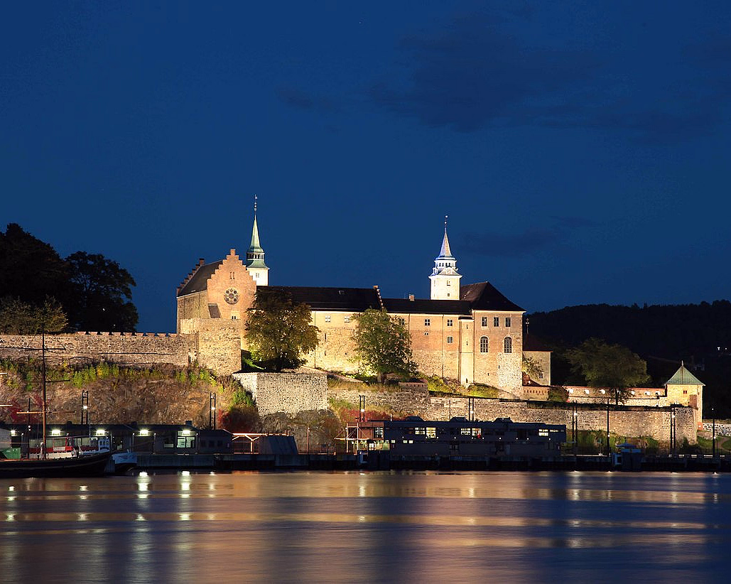 Opplyst festning ved vannet i kveldsmørket