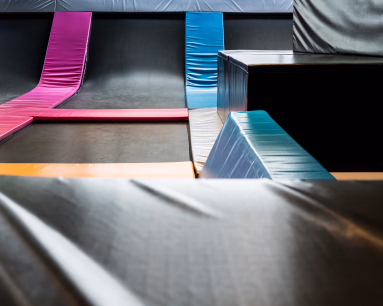 Innendørs trampolinepark med fargerike polstringer og svarte hoppeflater