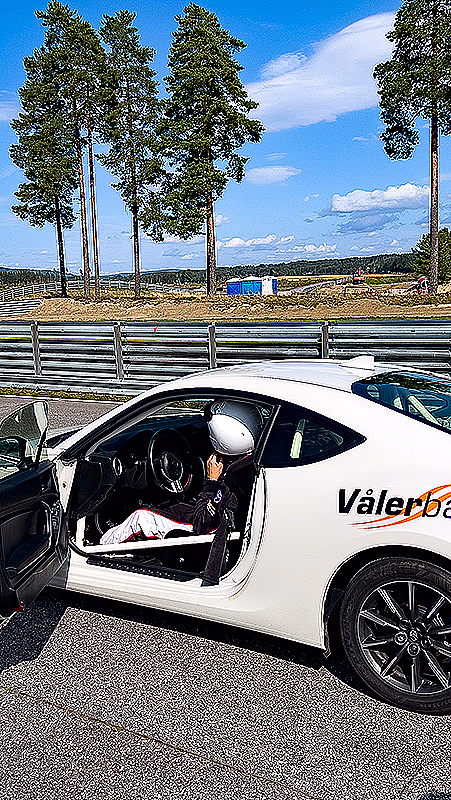 Person med hjelm i en hvit sportsbil med teksten Vålerbanen på siden