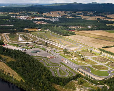 Flyfoto av en motorsportbane omgitt av skog og jorder