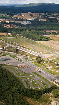 Flyfoto av en motorsportbane omgitt av skog og jorder