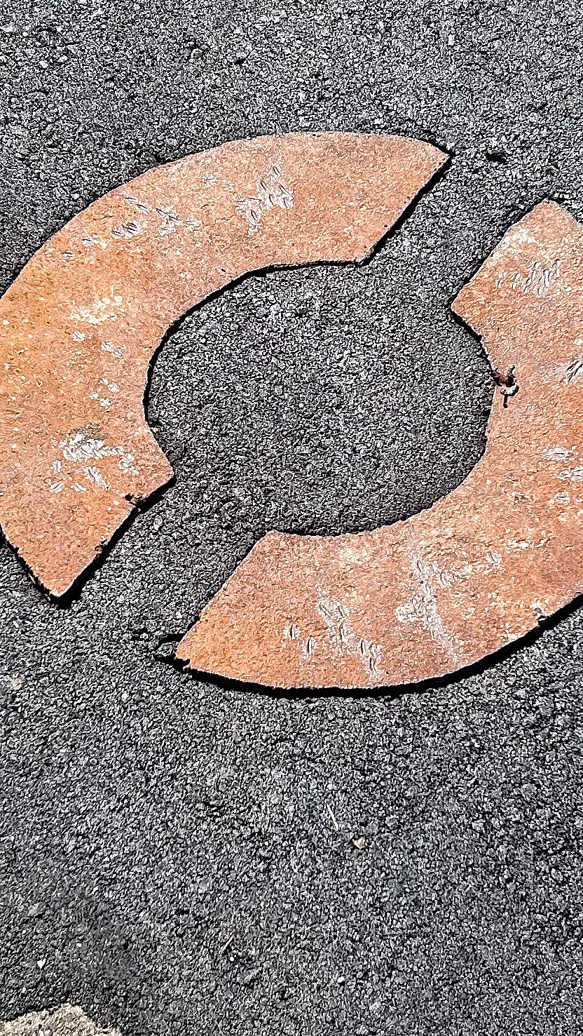 To rustne halvsirkler i metall formet som en sirkel på mørk asfalt