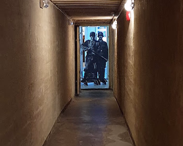 Lang, smal betongkorridor med to soldatfigurer i enden av gangen