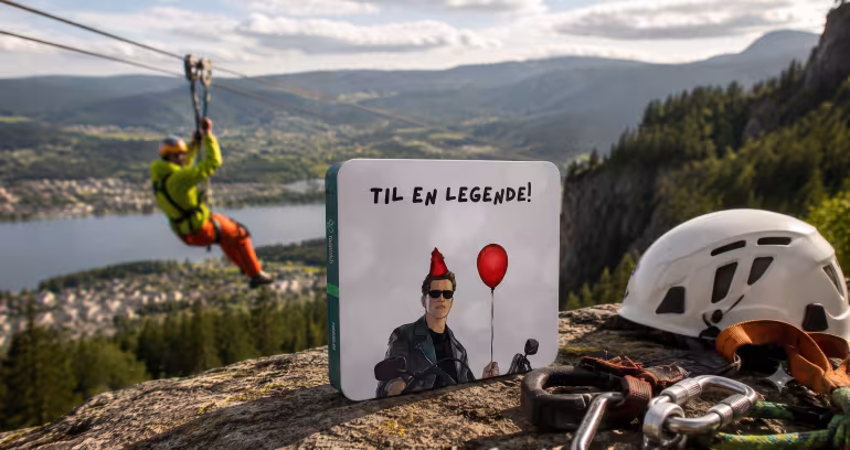 Gaveeske med teksten Til en legende foran klatreutstyr og en person i zipline