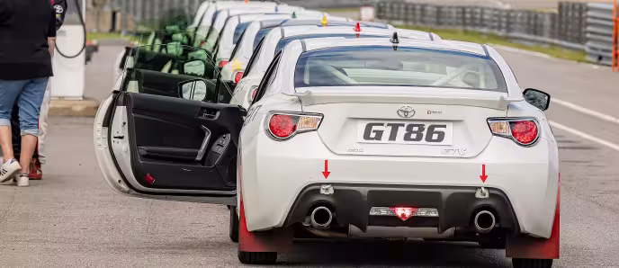 Hvite sportsbiler med teksten GT86 oppstilt på en racerbane