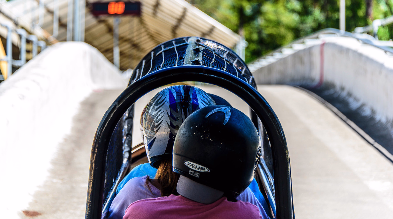 To personer med hjelmer i en bobslede på en bane med høye vegger