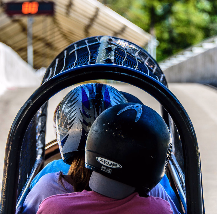 To personer med hjelmer i en bobslede på en bane med høye vegger