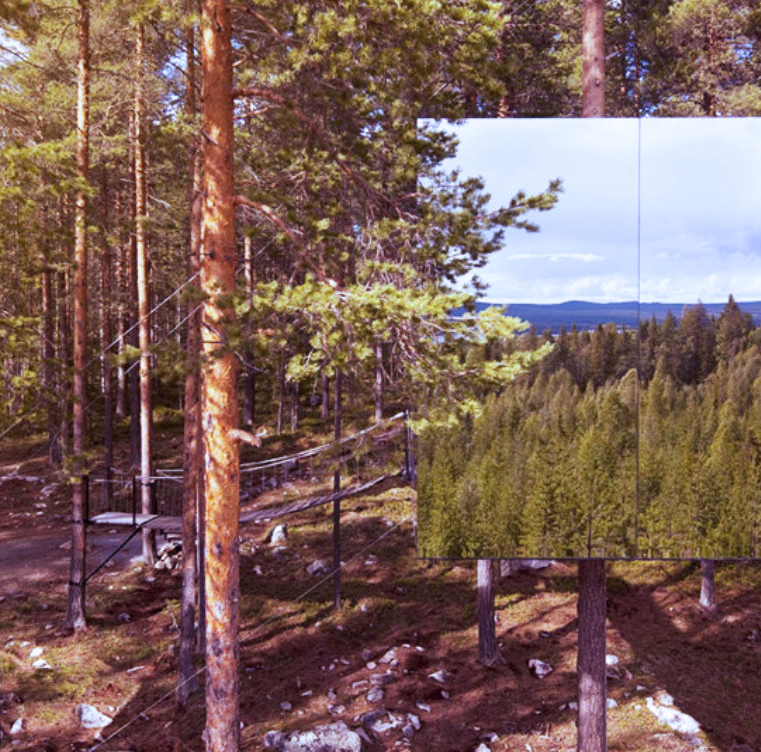 Stort speil i en skog som reflekterer trær og en blå himmel med skyer