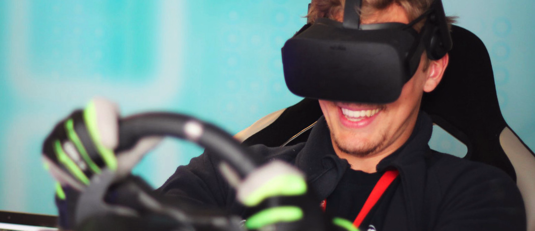Smilende person med VR-headset i et racingsete som holder et ratt