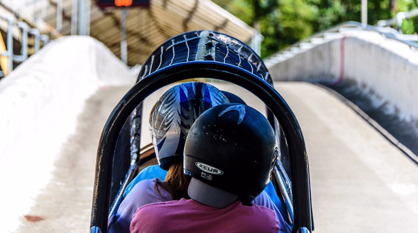 To personer med hjelmer sitter i en bobsleigh på en isbane