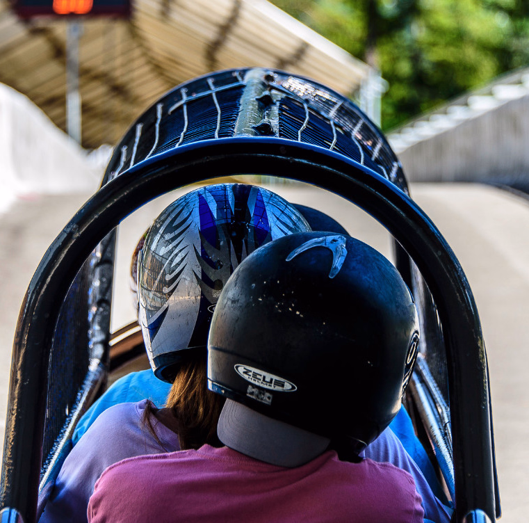 To personer med hjelmer sitter i en bobsleigh på en isbane
